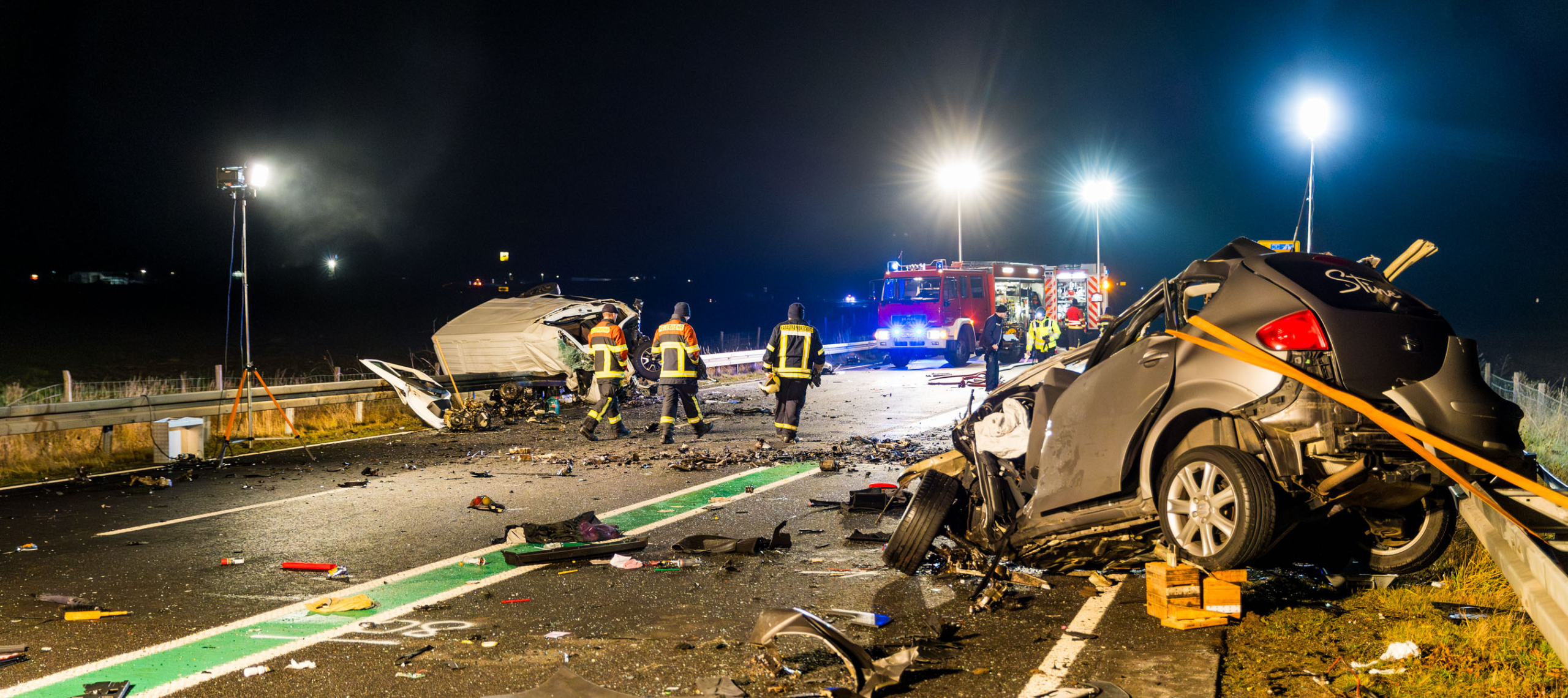 Zwei vollkommen zerstörte Autos nach einem tödlichen Verkehrsunfall auf der B169 im Hintergrund Polizei und Feuerwehr