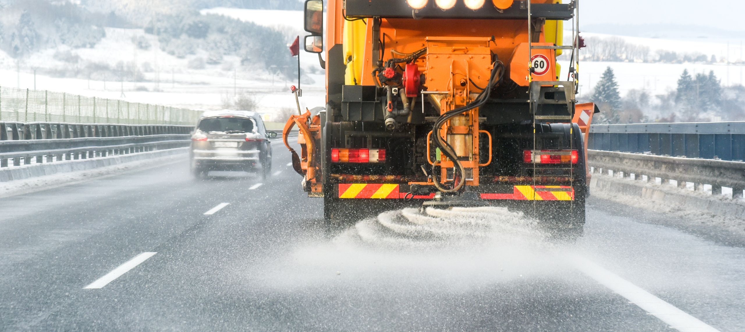 Ein Streufahrzeug streut Salz auf einer eisglatten Straße