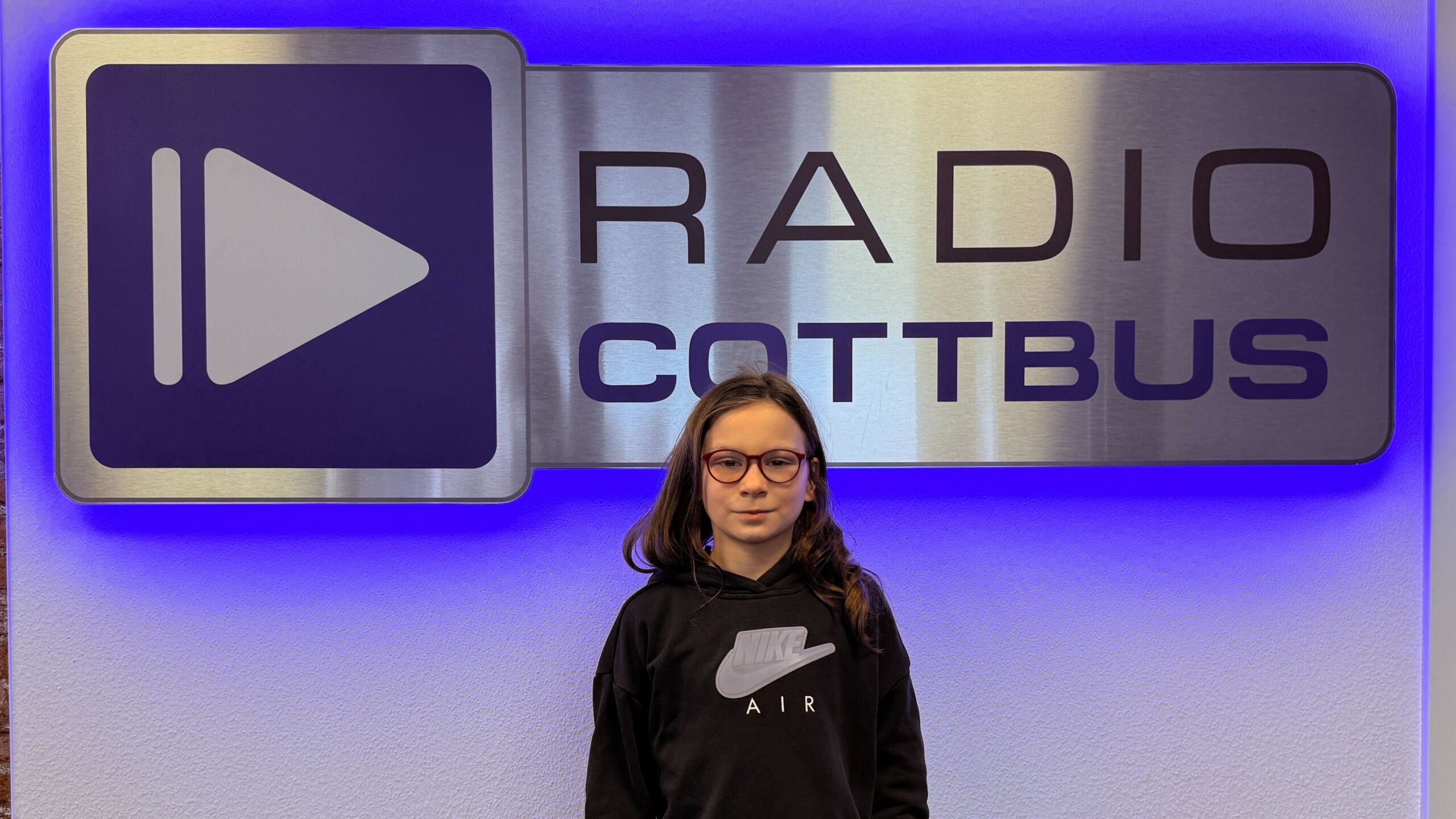 Teja Rückmann vor dem Radio Cottbus Logo