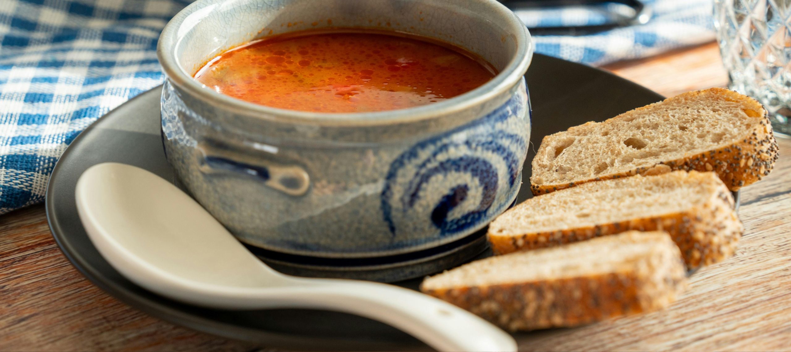 Vegetarische Soljanka angerichtet in einer kleinen blauen Schüssel mit drei Stück Brot an der Seite