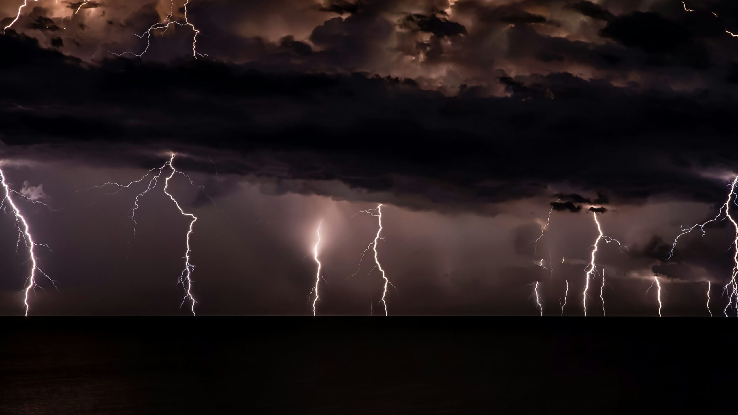 Ein dunkler Himmel bei Unwetter und mehrere Blitze kommen aus den Wolken raus