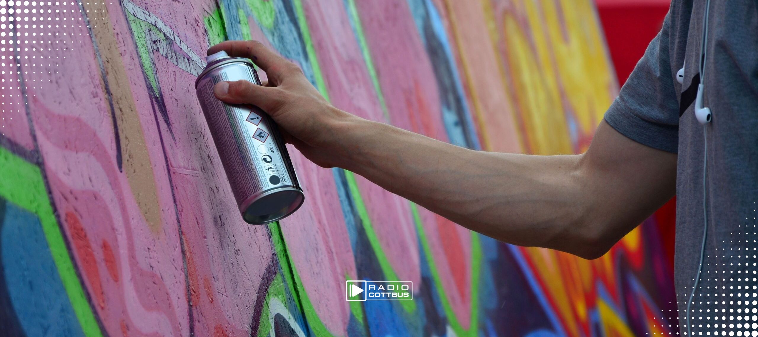 Ein unbekannter Mann sprüht mit einer Graffitidose eine wand bunt an