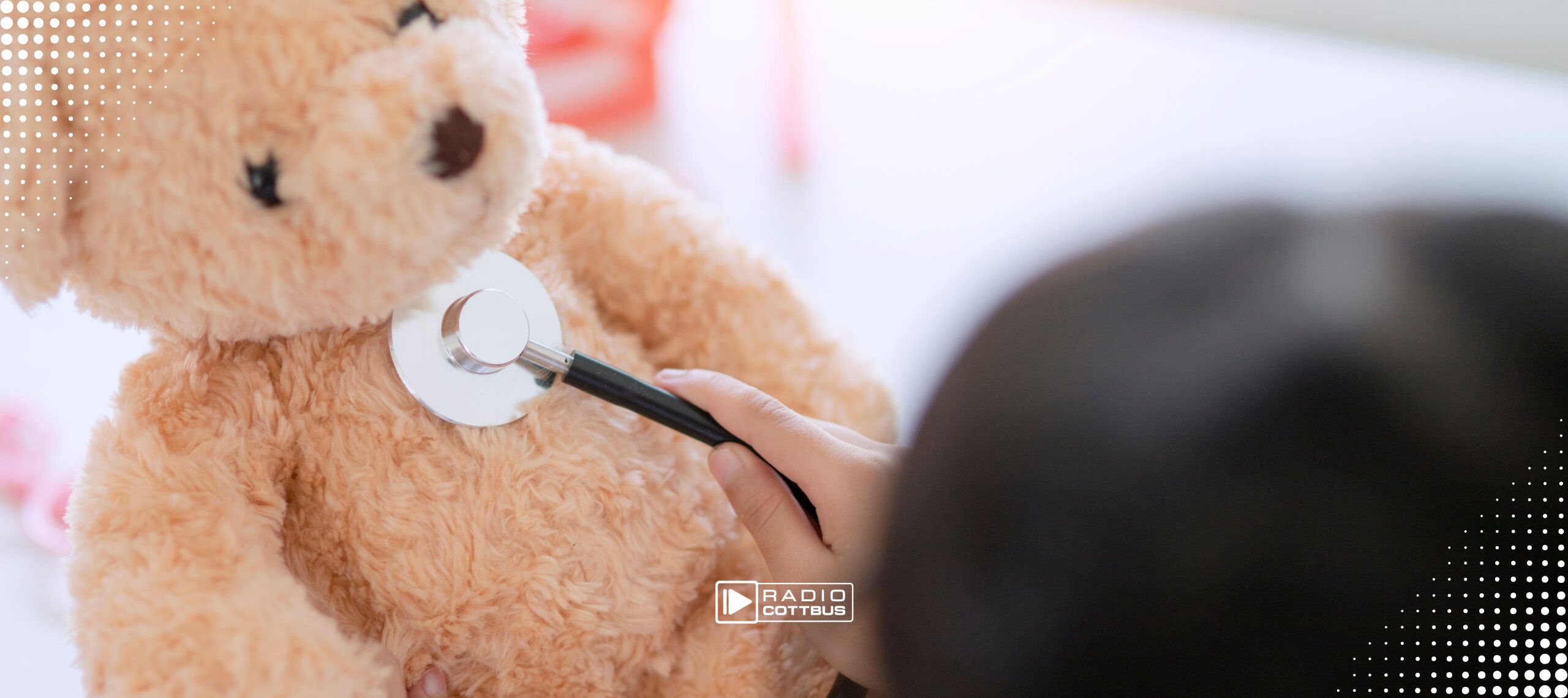 Ein Kind hört mit einem Stetoskop einen Teddybär ab