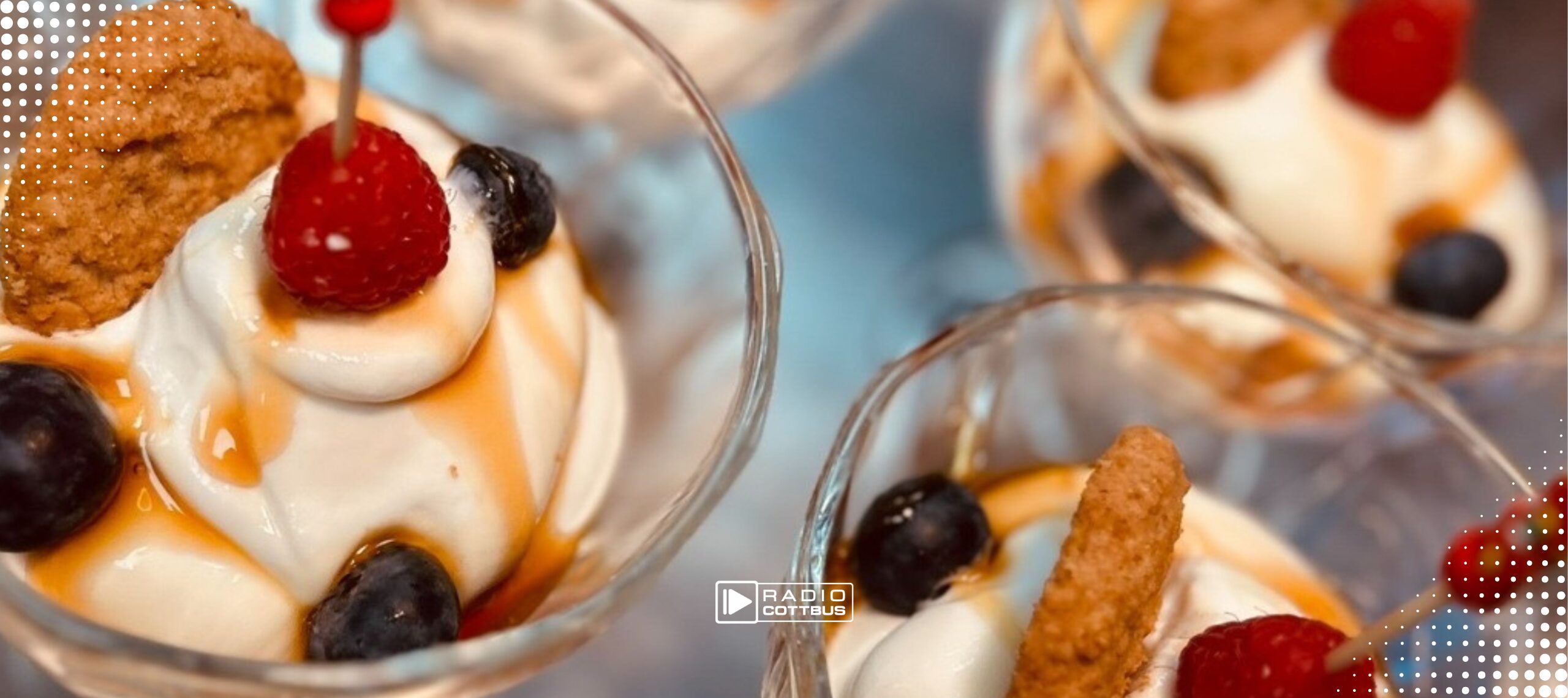 Mehrere Sahnedesserts in Gläsern mit Früchten und Keksen obendrauf