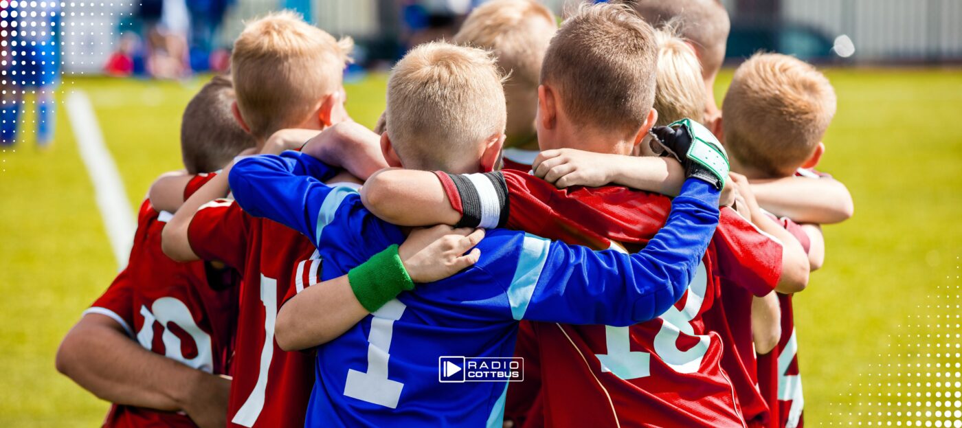 Mehrere Jungs umarmen sich auf einem Fußballplatz
