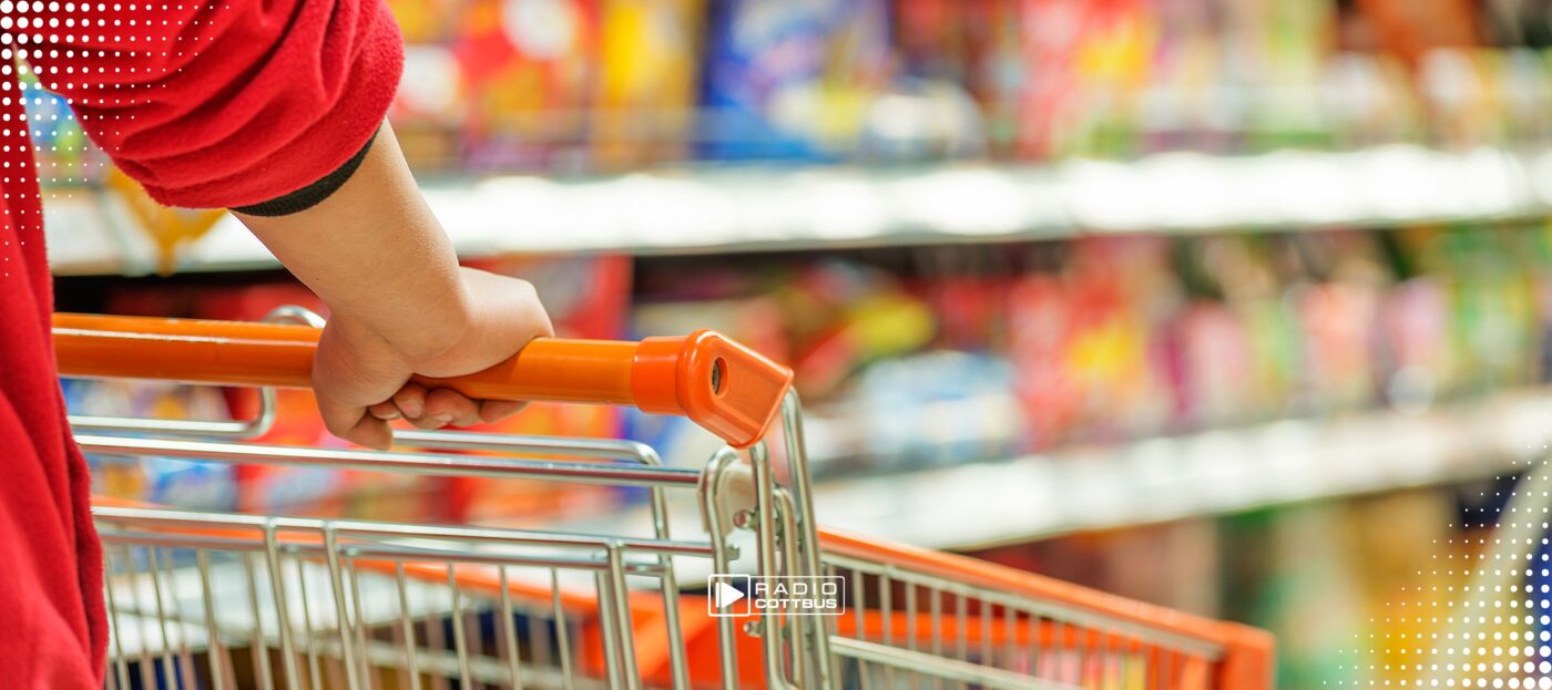 ein Mensch geht mit einem Einkaufswagen durch den Supermarkt